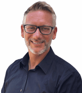 Kay Jaeger, CEO von Social@ALL und der jaegermediagroup.de Ein l&auml;chelnder Mann mit kurzem, hellem Haar und gestutztem Bart, der eine schwarz umrandete Brille und ein dunkles Button-up-Hemd tr&auml;gt, steht vor einem schlichten wei&szlig;en Hintergrund - bereit, sich &uuml;ber social@all mit der Welt zu verbinden.